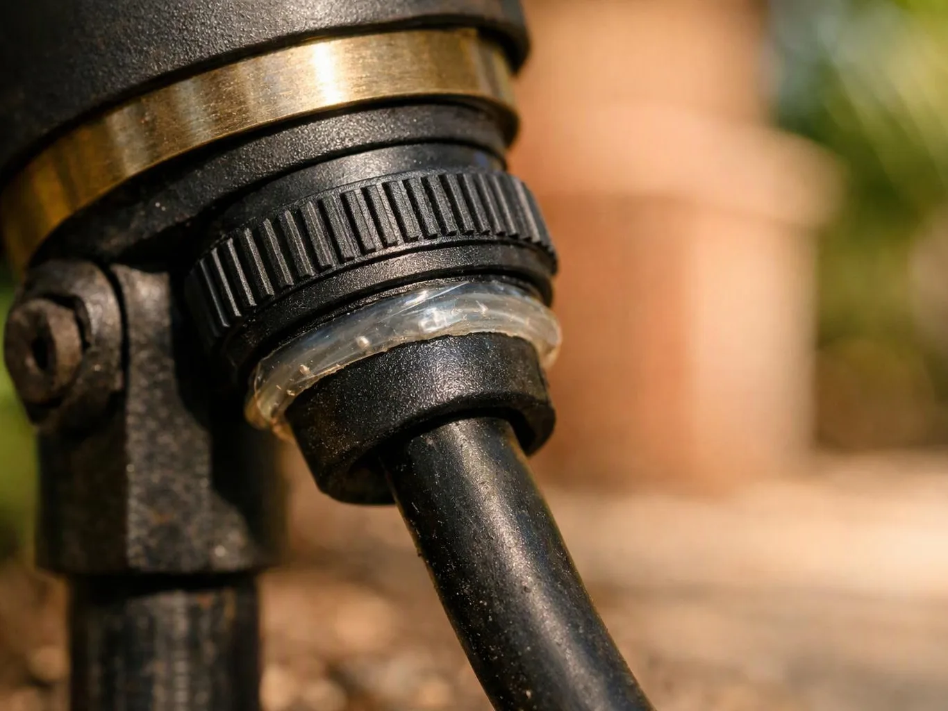 A close-up shows a black cable fitting with a ridged collar and clear seal against a blurred outdoor background