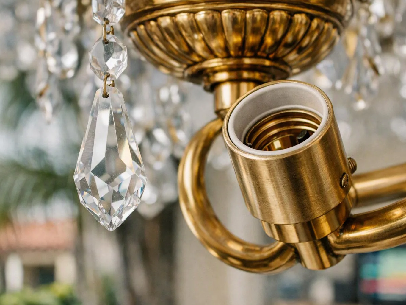 A gold chandelier socket hangs beside clear crystal drops in a close-up interior scene
